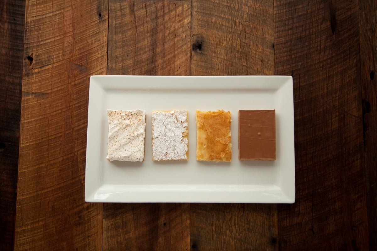 4 pieces of desserts on a rectangular plat in a wooden table