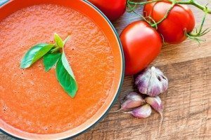 Tomato Basil Soup with raw tomatoes and onion bulb beside it